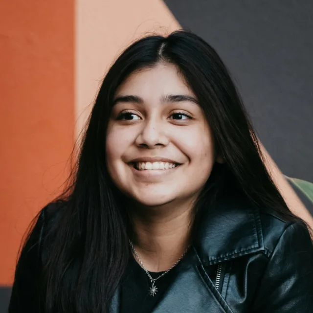 Smiling teenage girl with long dark hair, in a black leather jacket