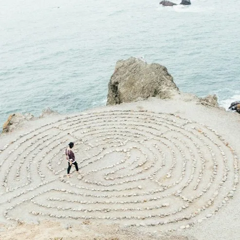 Person walking through a stone labyrinth by the sea